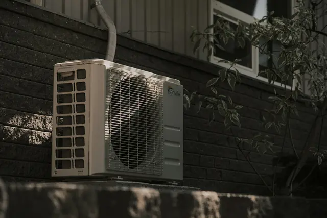 An air conditioning condenser beside a brick wall