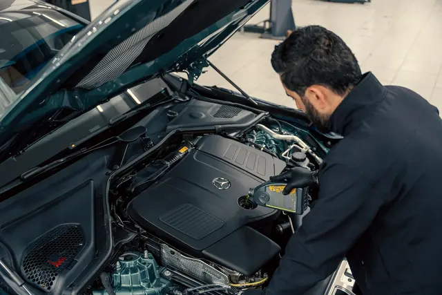 A mechanic inspecting a car engine with the hood open