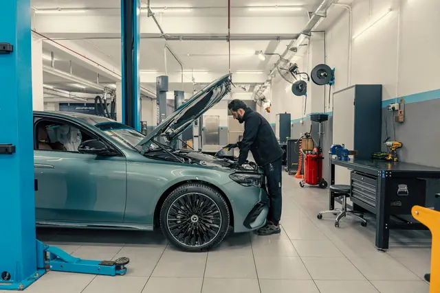 A mechanic working under the hood of a car in a clean repair shop