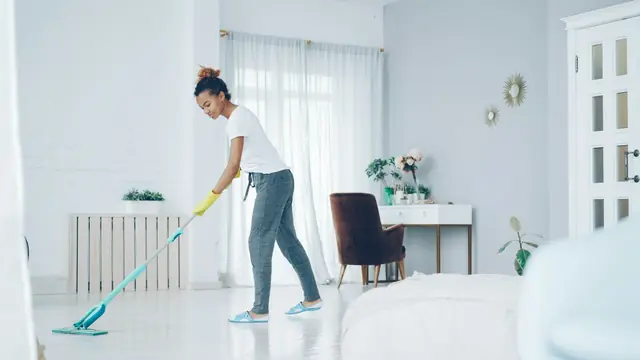 A cleaner mopping the floor of a bright living room