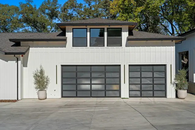 A modern white house with two glass-panel garage doors