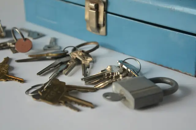 Keys and a padlock on a table beside a blue toolbox