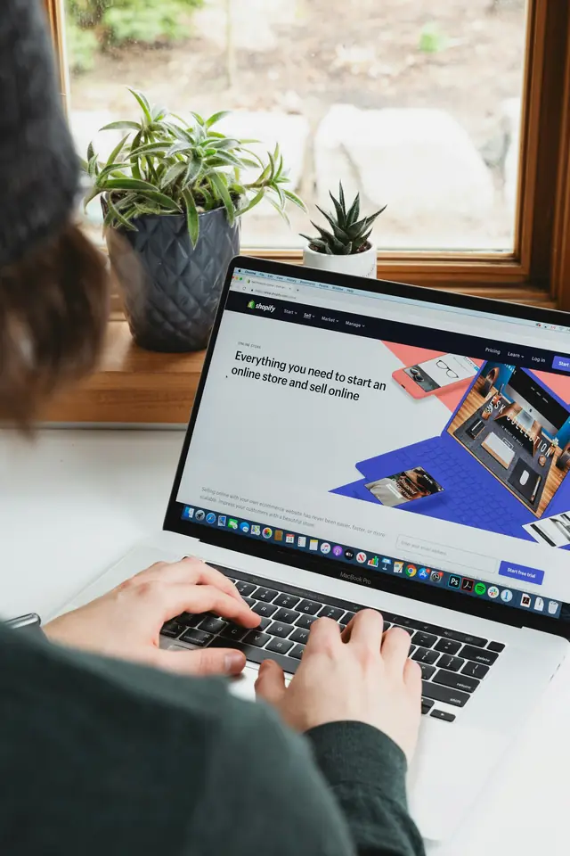 Hands typing on a laptop showing a business website