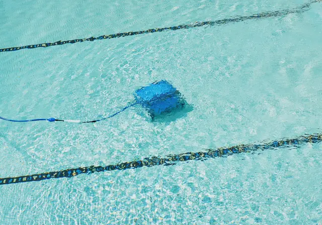 A robotic pool cleaner working on the floor of a pool