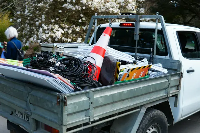 A white work truck with tools and cable reels in the bed